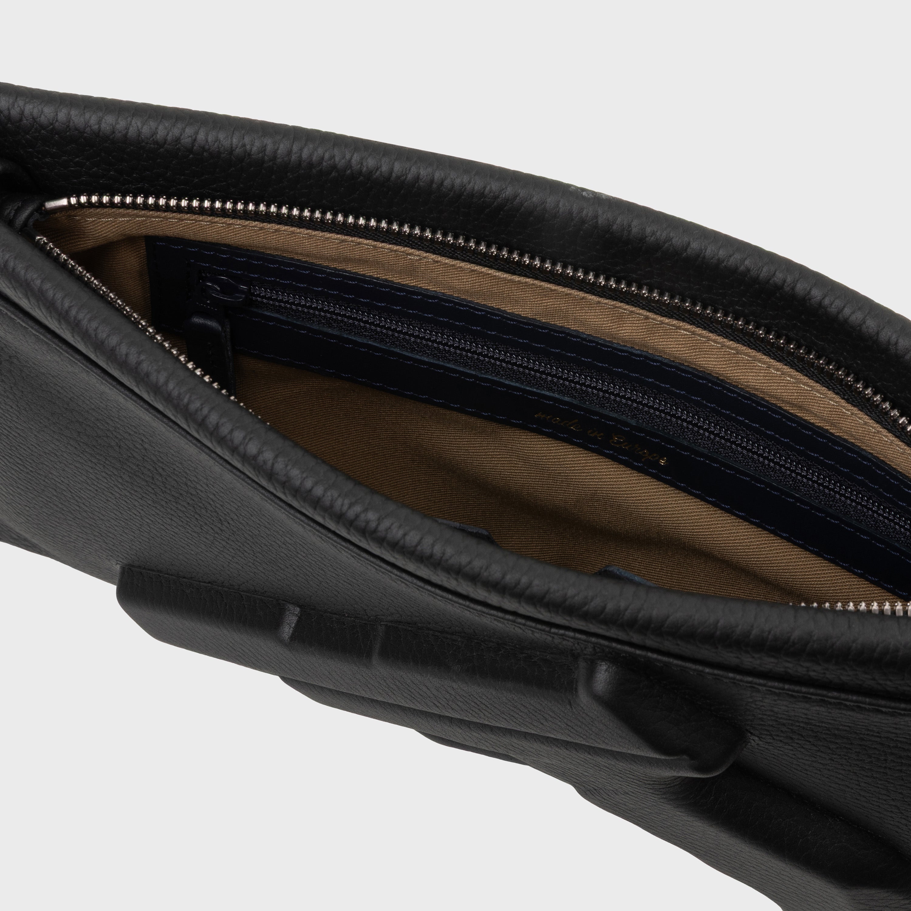 Close-up of a black leather bag with a zipper on a light gray background